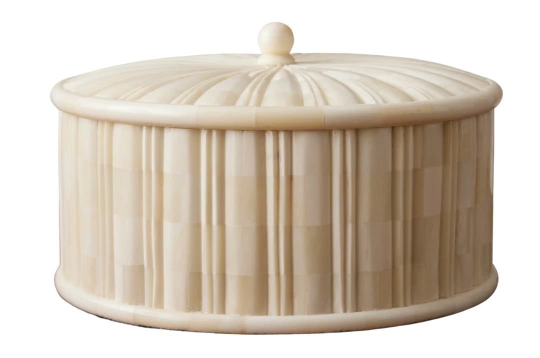 Decorative ivory-hued jar with natural bone inlay and sculptural lid detail.