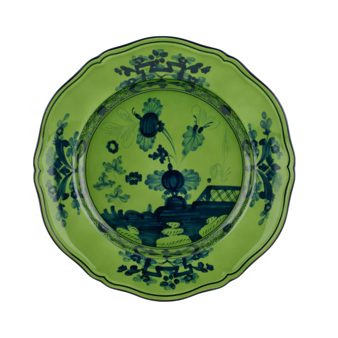 A vibrant green ceramic plate featuring scalloped edges and an intricate navy blue chinoiserie-style motif.