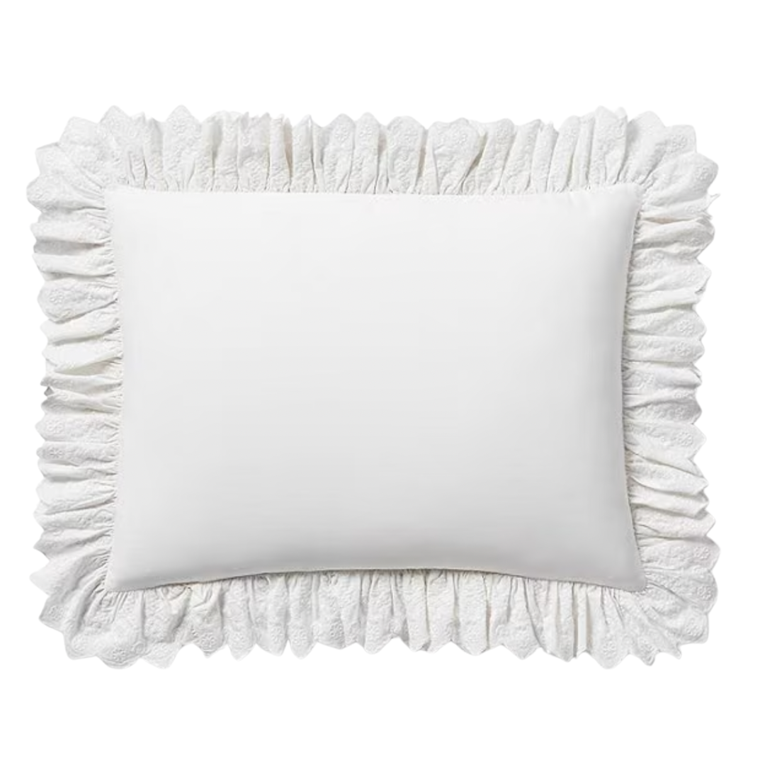 A rectangular white throw pillow with a wide, textured ruffle border, adding a soft, romantic touch.