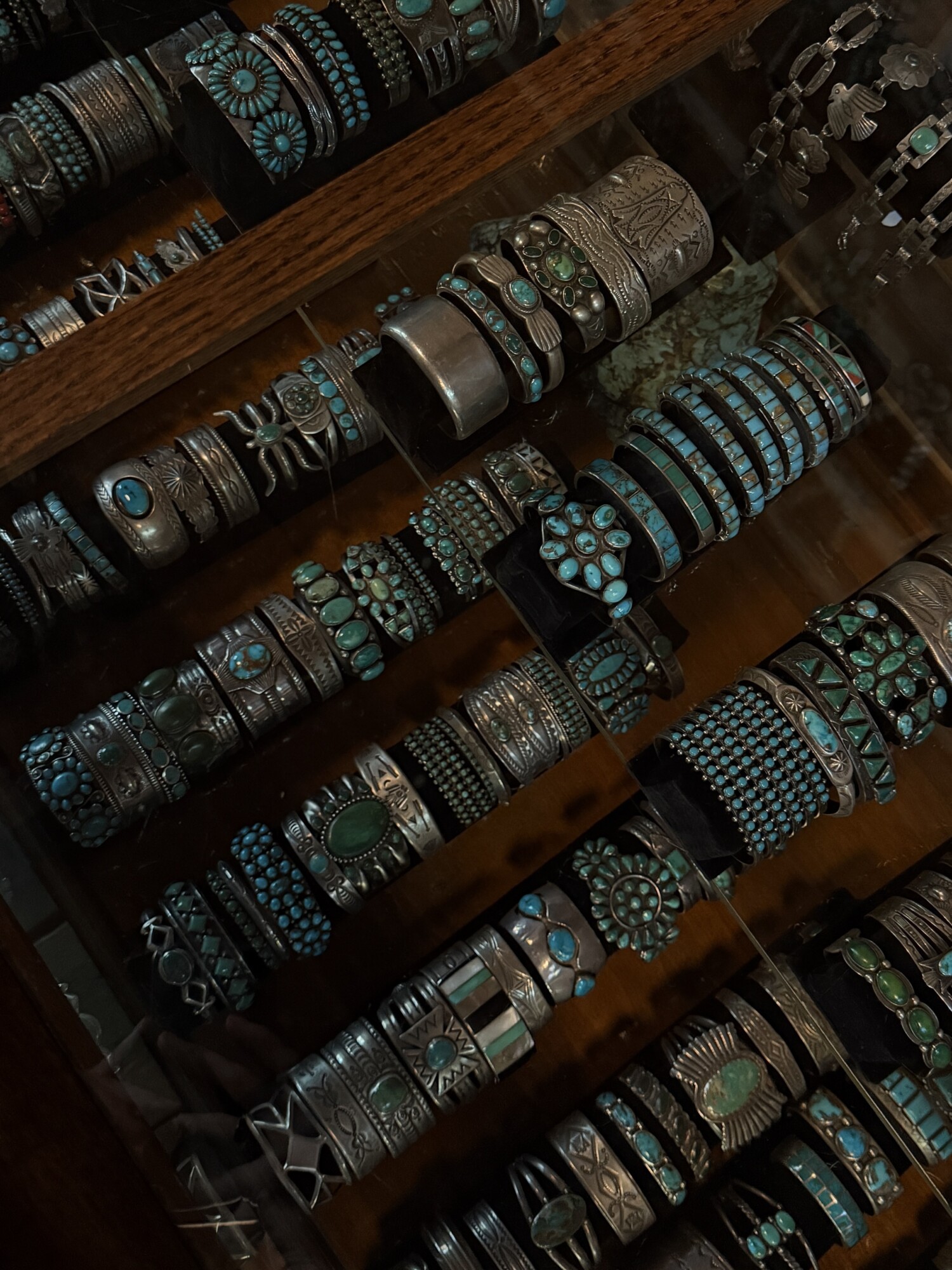 Glass display case packed with vintage sterling-silver and turquoise cuffs, bracelets, and rings inside a jewelry shop.
