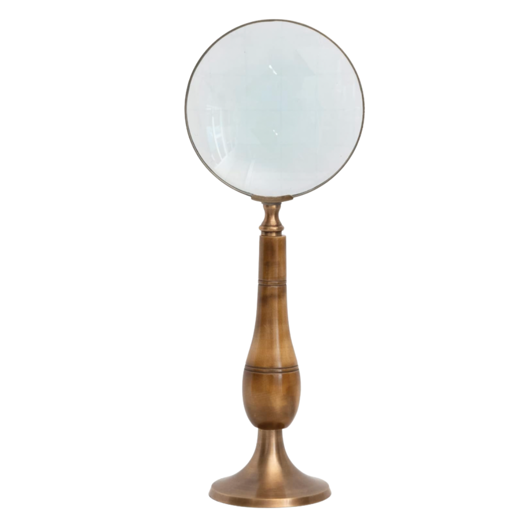 Vintage-inspired magnifying glass on a brass stand with bone detail—decorative desk or console accent.