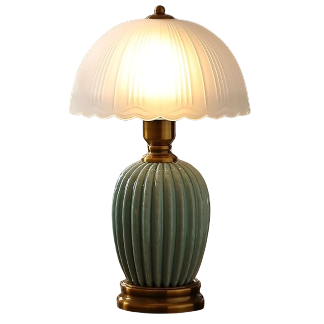 Old-world table lamp with ribbed green base, brass accents, and scalloped frosted shade glowing warmly.