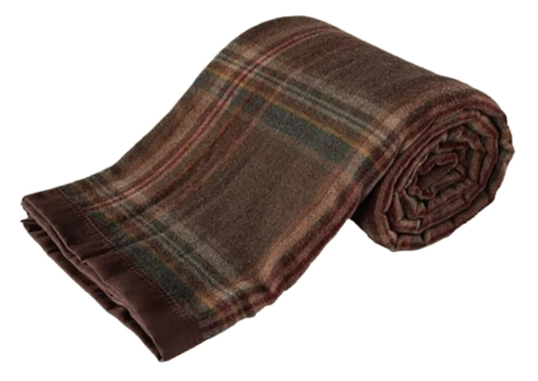 A rolled 100% pure merino wool blanket in a rich brown plaid pattern with subtle tones of green, red, and gold. The edges are neatly finished with a matching brown border, giving it a tailored and timeless look. The soft, medium-weight texture hints at warmth and comfort—perfect for layering across a sofa or at the foot of a bed.