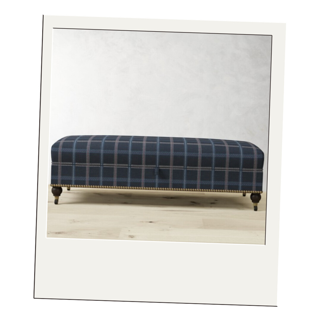 A navy and brown plaid upholstered bench with turned legs and brass nailhead trim, perfect for a cozy traditional touch.