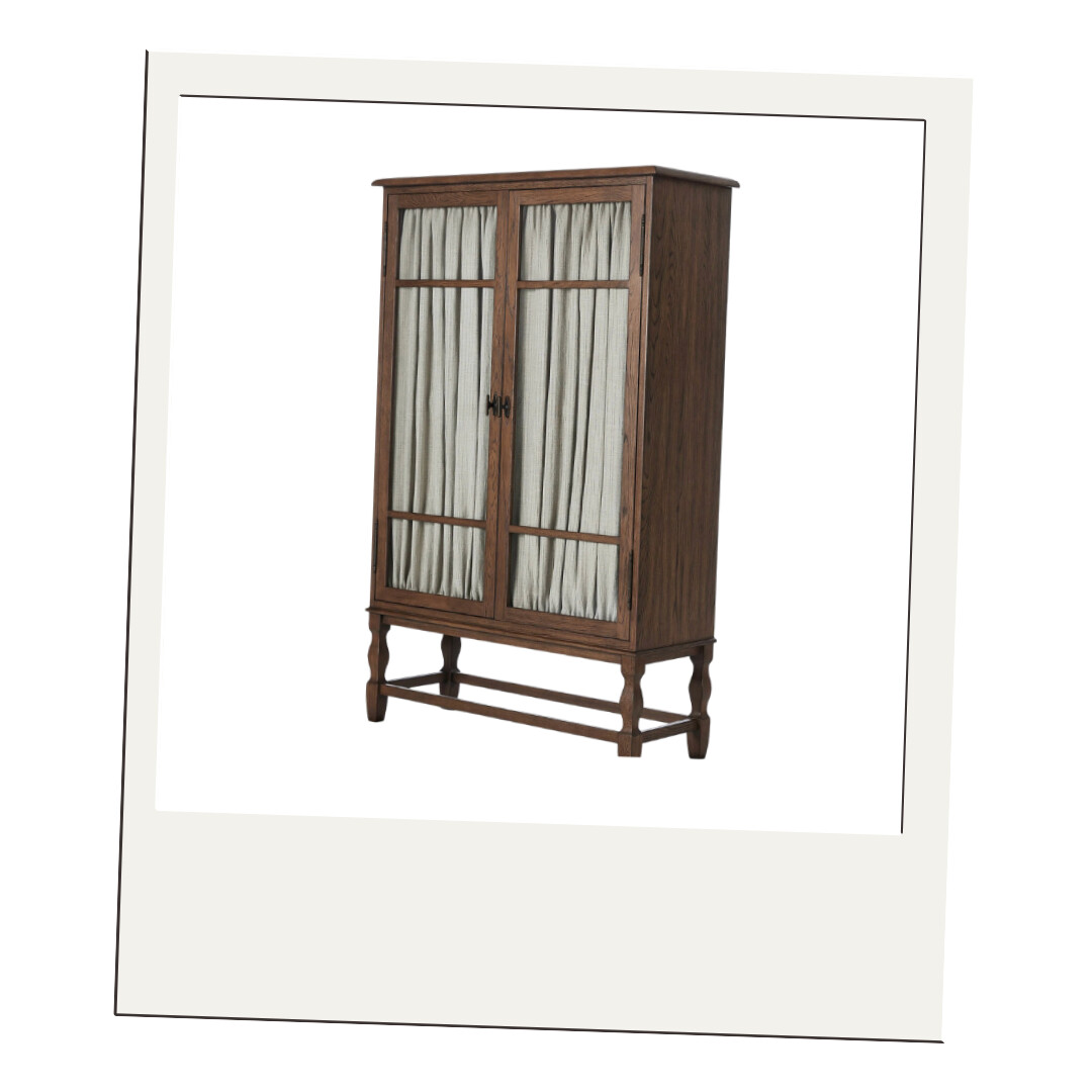 Tall wooden cabinet with linen-covered glass doors and turned legs, showcasing traditional craftsmanship and warmth.