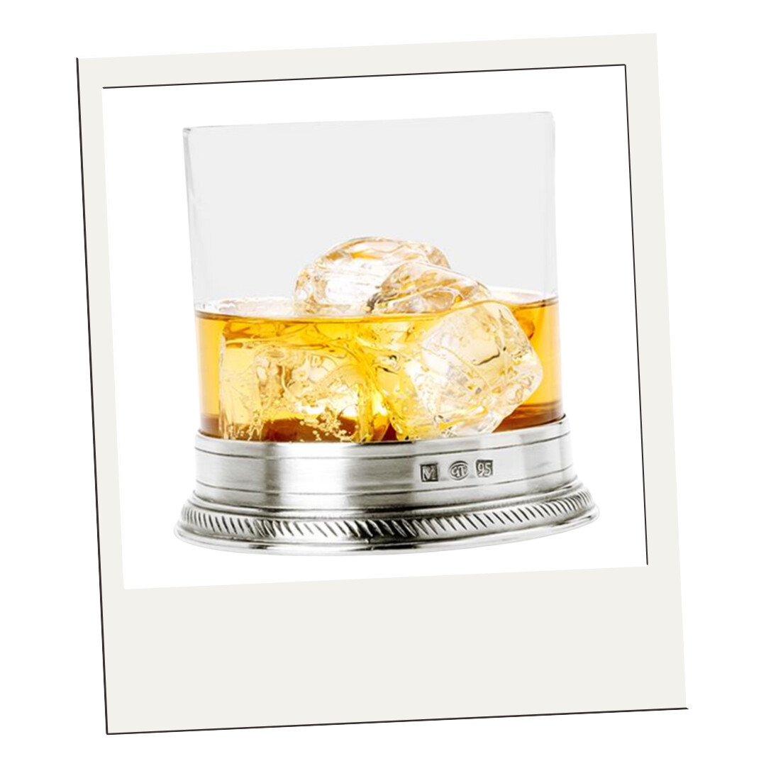 Silver whiskey tumbler with cut crystal glass and sterling base, filled with amber whiskey and ice cubes.