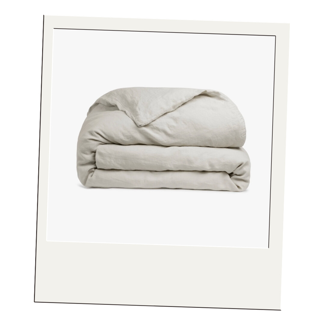 A soft, neutral linen duvet folded neatly, showcasing its relaxed texture and cozy, organic feel.