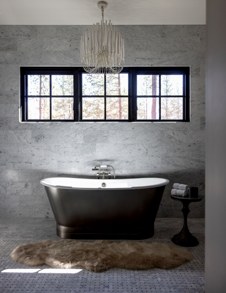 1. Luxury bathroom with freestanding black bathtub, marble tile walls, large black-framed windows, and modern chandelier.