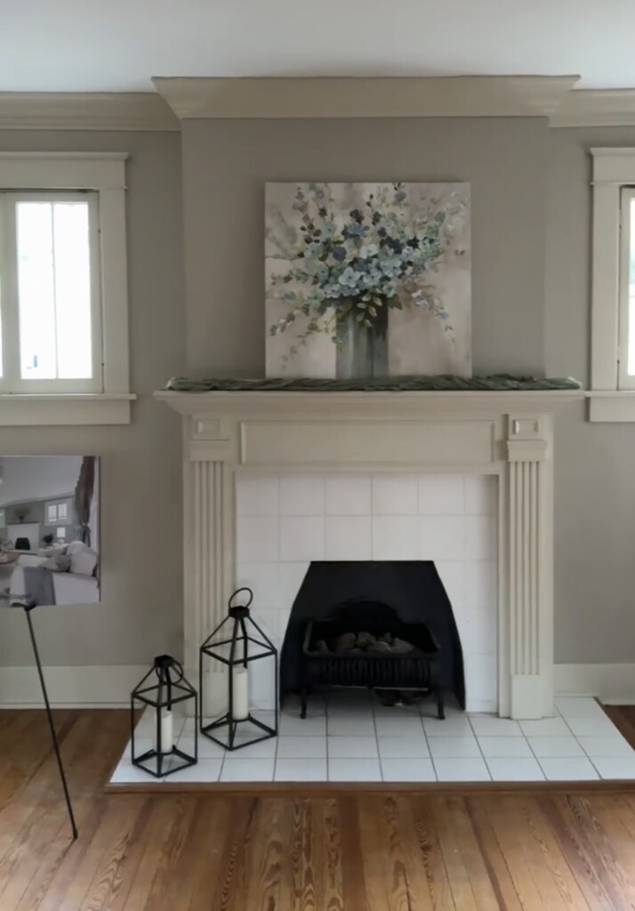 Outdated white tile fireplace with traditional mantel surround and hardwood floors before renovation update.