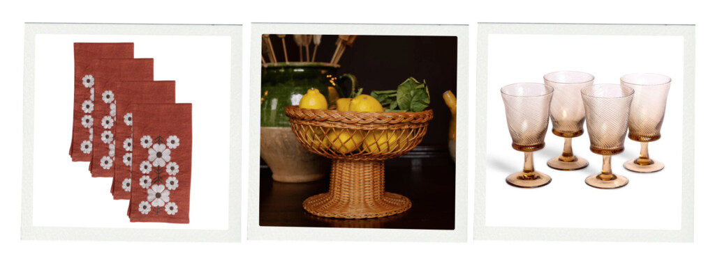 A tabletop grouping with embroidered rust-colored napkins, a woven pedestal fruit basket filled with lemons, and a set of amber-toned drinking glasses.