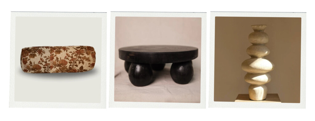 A mix of furniture and decor including a floral upholstered cushion, a low dark wood stool with rounded legs, and a sculptural stacked stone-like object in a warm neutral finish.