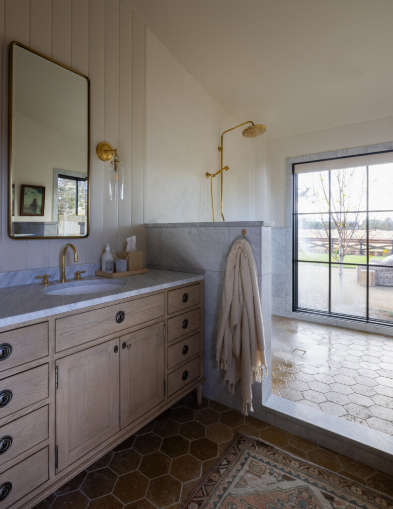 Light-filled bathroom with marble shower, wood vanity, and soft neutral towels for a warm, lived-in feel