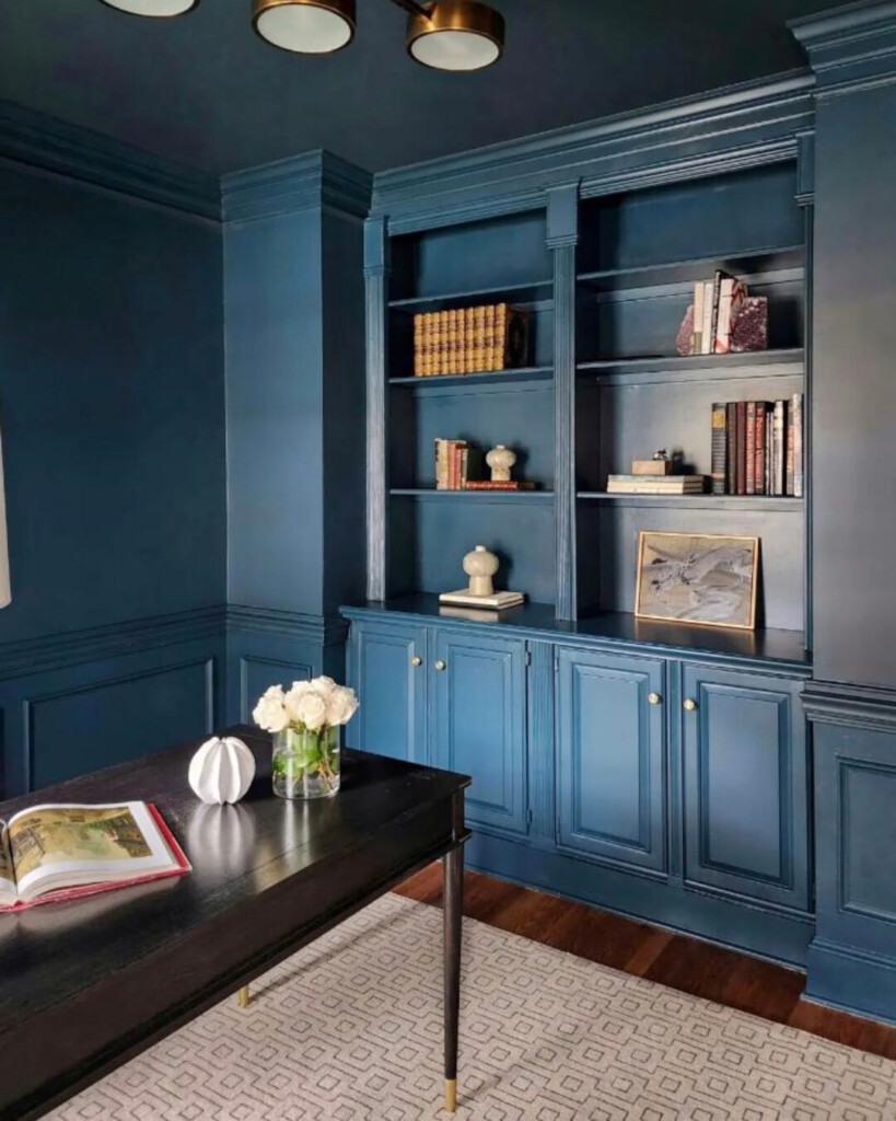 A deep navy built-in office with cabinetry, warm wood desk, brass lighting, and layered textures for a tailored, sophisticated look.